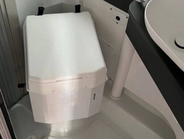 Weiße Trenntoilette eingebaut im Bad eines Wohnmobils, rechts daneben das Waschbecken